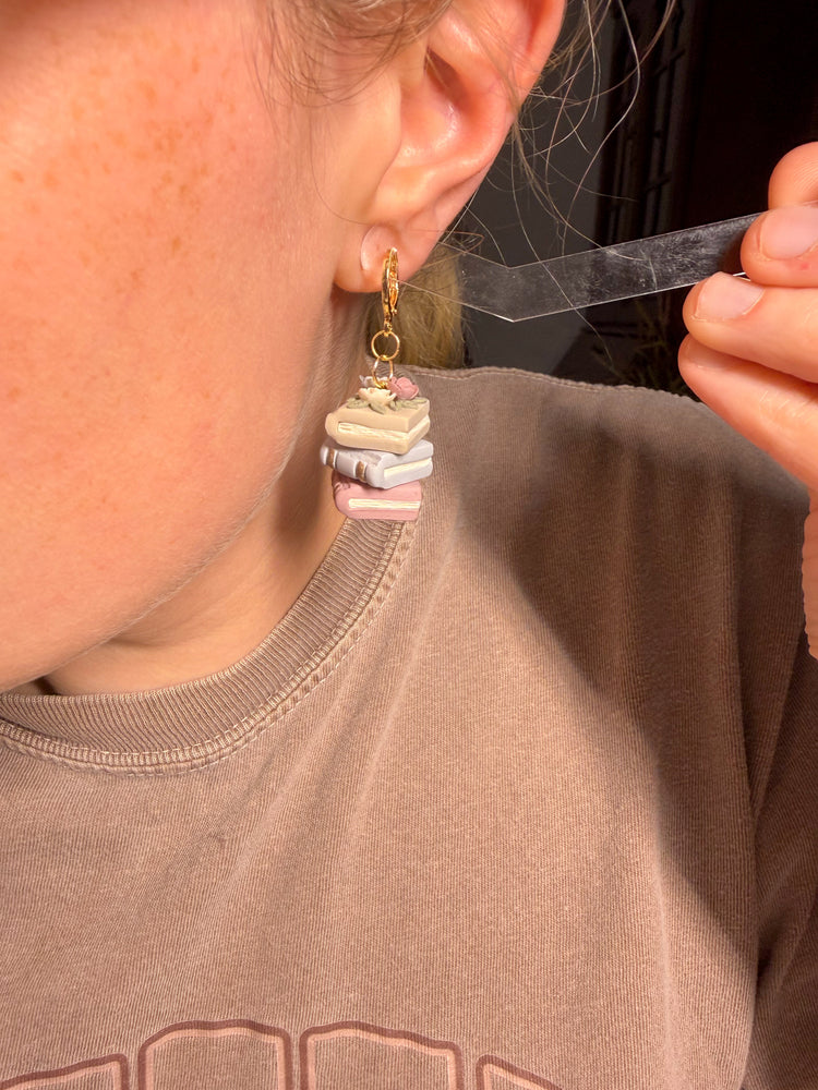 Person showing size reference next to ear of the stacked earring books