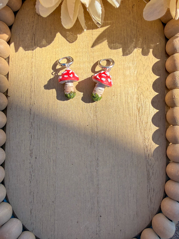 Pair of mushroom-shaped earrings on a wooden surface