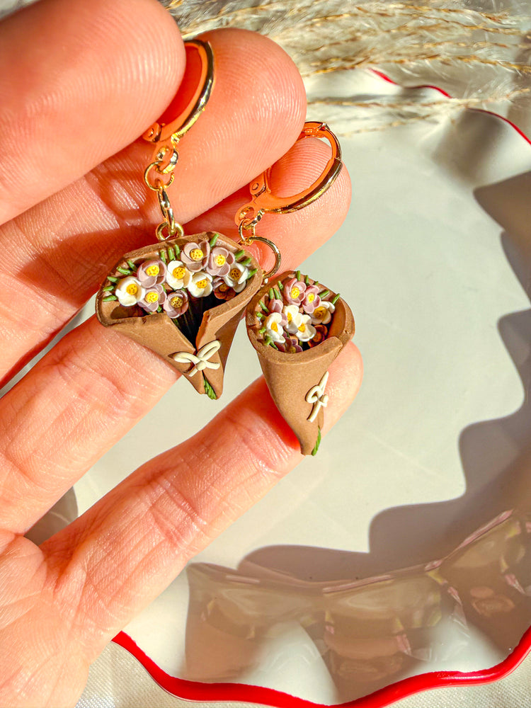White and lilac colored flowers with green flower stems in flower bouquet earring with gold lever back earring post