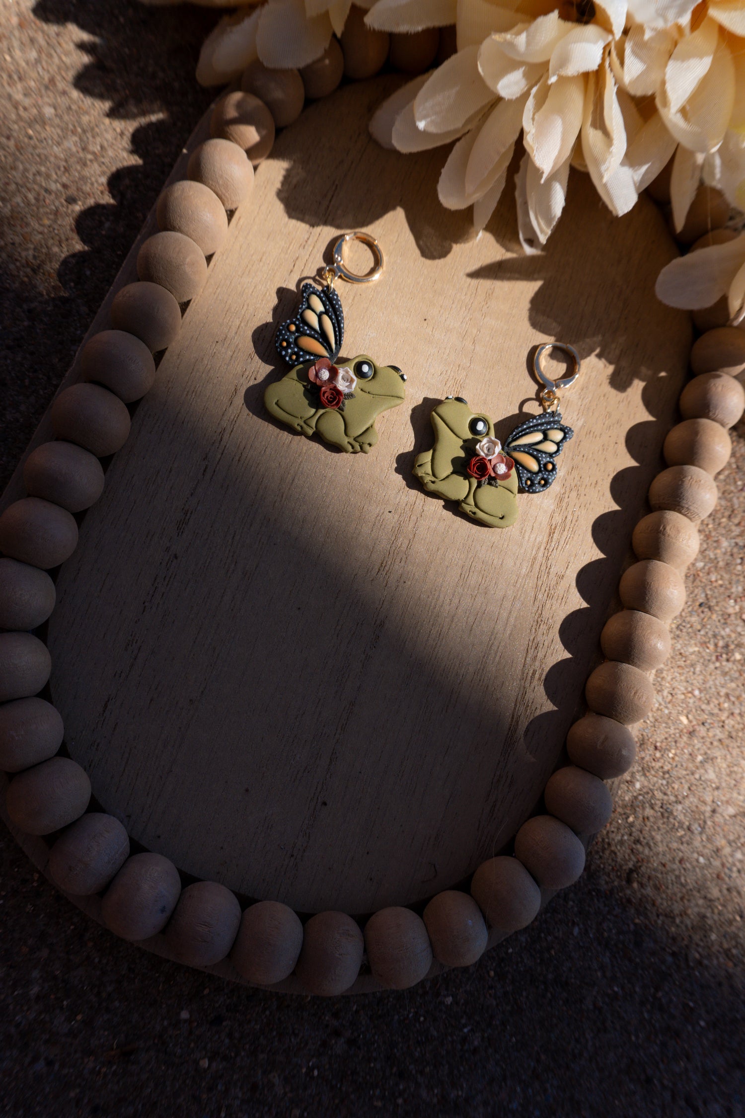 Mystical frog earrings with neutral flowers and monarch butterfly wings.