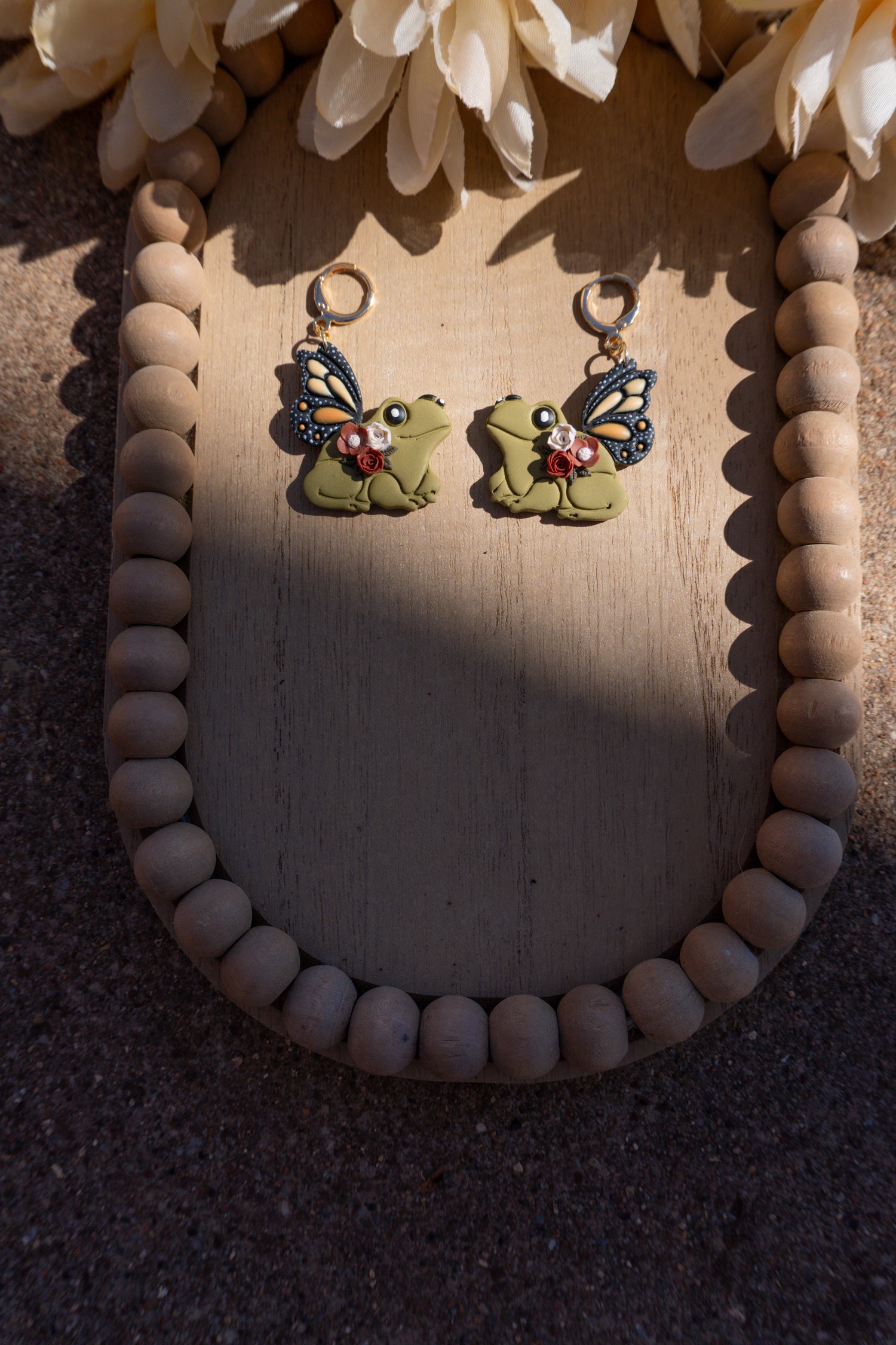 Frog shaped earrings with butterfly wings and floral accents