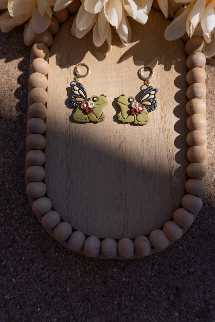 Frog shaped earrings with butterfly wings and floral accents