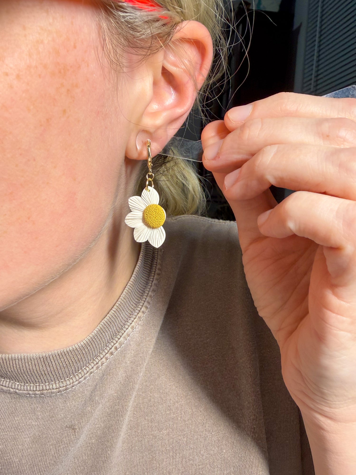 Person wearing white daisy earrings