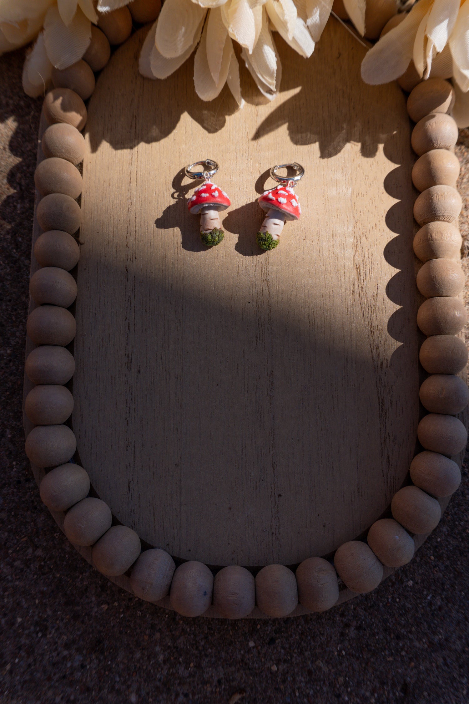 Mushroom-shaped earrings on a wooden surface with decorative elements.