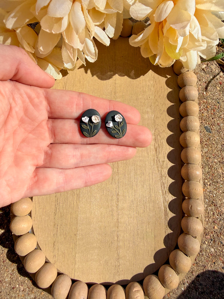 Oval black clay earrings with neutral colored roses