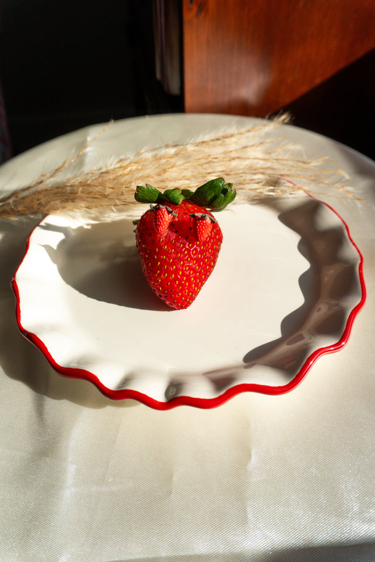 Strawberry clay stud earrings sitting on a real strawberry as a prop