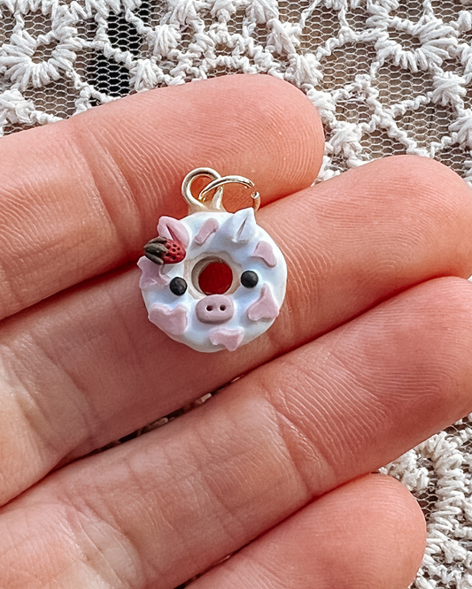 Pink cow charm with strawberry in the shape of a donut.