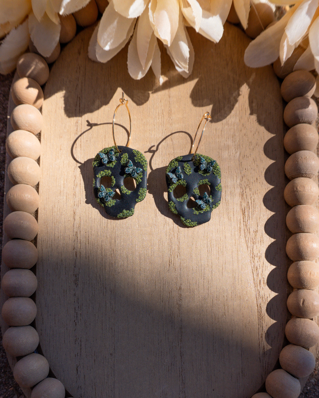 Pair of black skull dangle earrings with moss and hunter green butterflies.