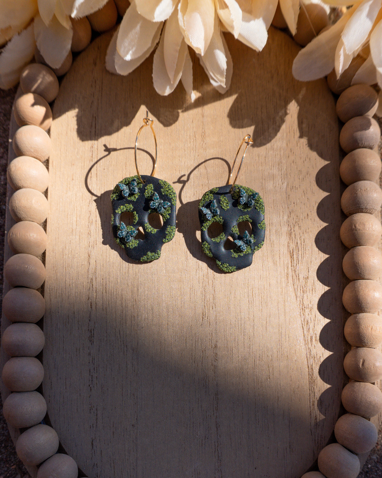 Pair of black skull dangle earrings with moss and hunter green butterflies.