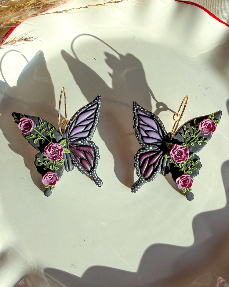Butterfly-shaped earrings with floral details on a light background