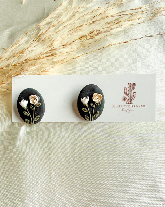 Black oval stud earrings with white and cream colored roses
